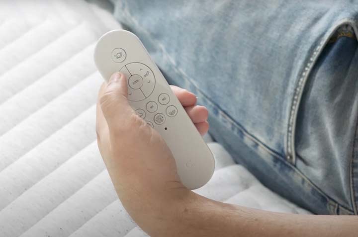 A hand holds the Casper Rise Remote over the surface of a mattress