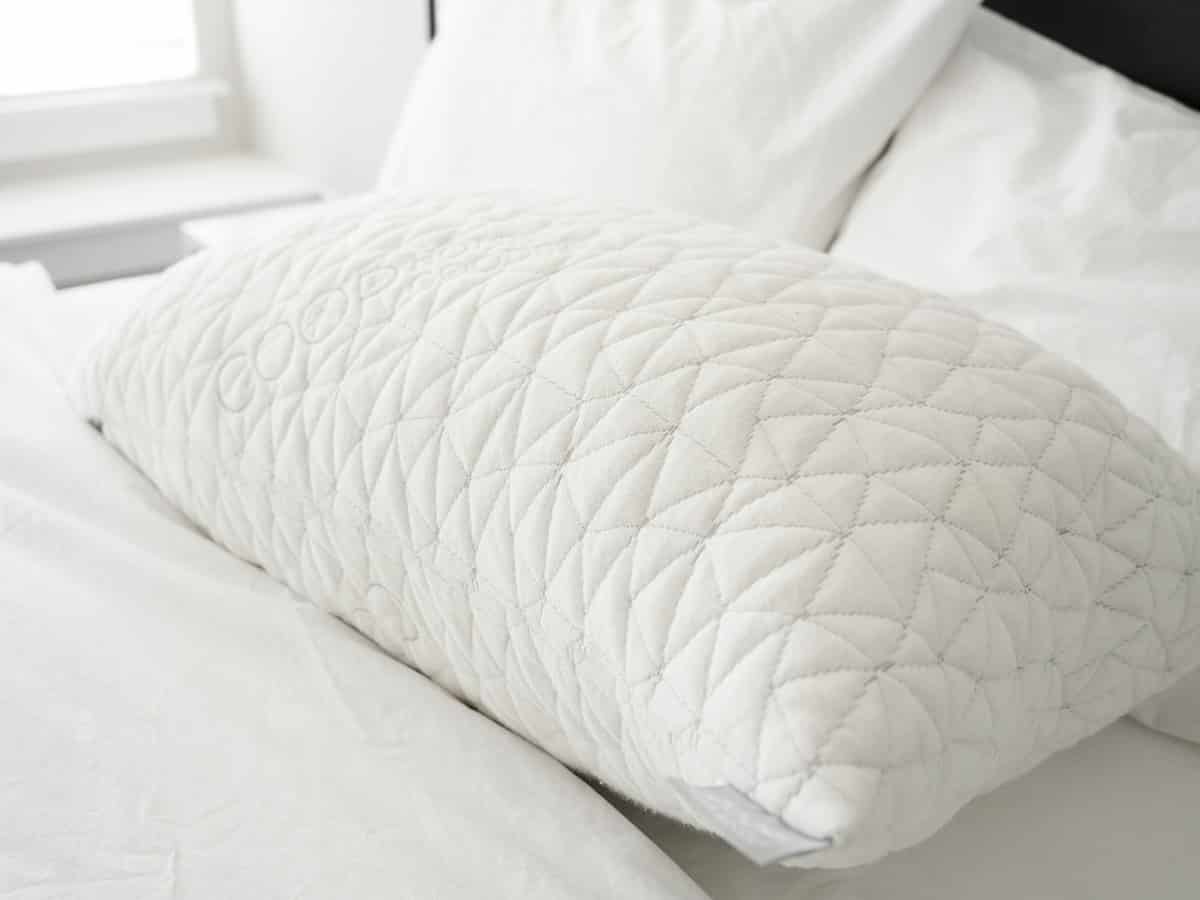 A Coop Original Pillow sits on a bed.