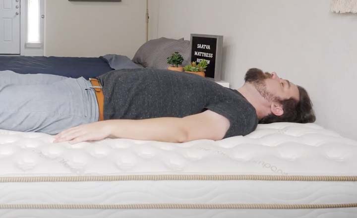 A man sleeps on his back on the Saatva mattress.
