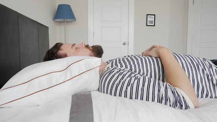 A man sleeps on his back on the Saatva Pillow.