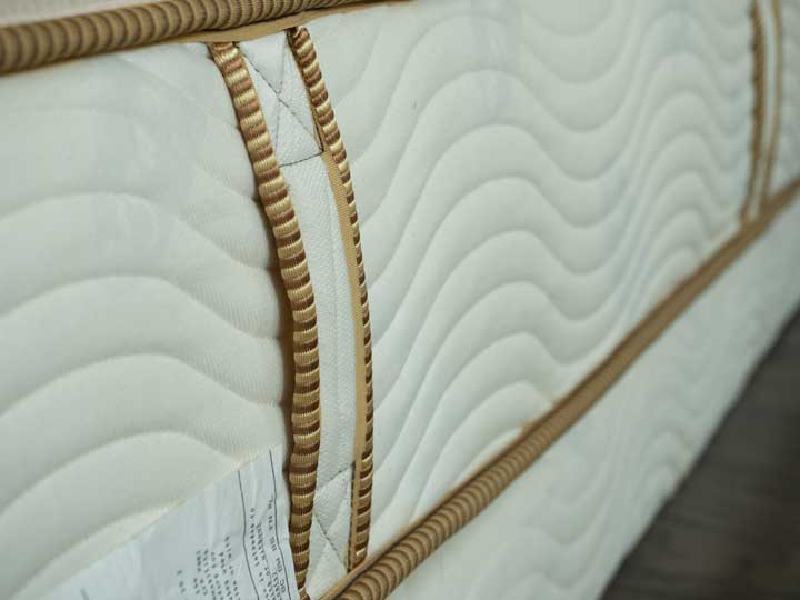 A view of the side of the Saatva Youth mattress with handles and organic fabric. 