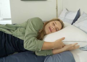 A woman sleeps on her side with the Sleep Number True Temp Pillow.