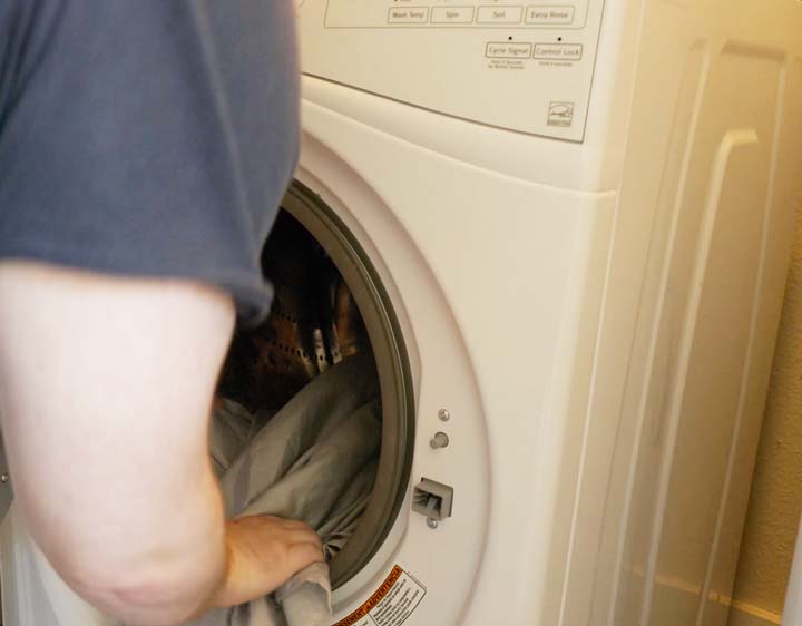 man loads the GhostBed sheets into a washing machine